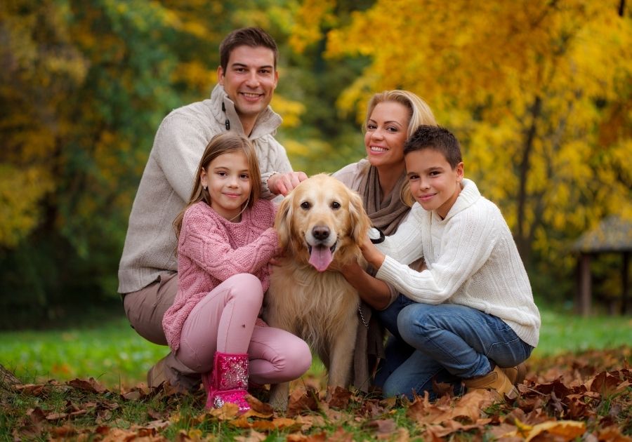 Happy Family Cuddling Their Golden Retriever Dog Outdoors