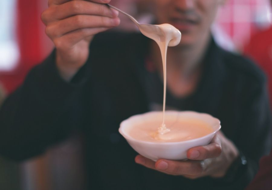 Man with Flowing Sour Cream from Spoon in White Bowl