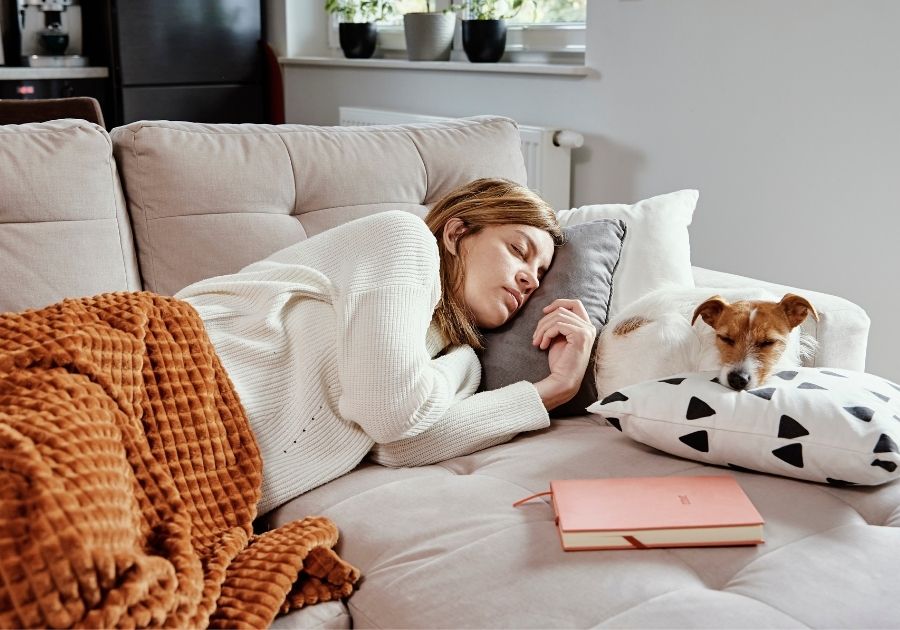 Woman Asleep While Dog Sleeps Facing Away on Sofa